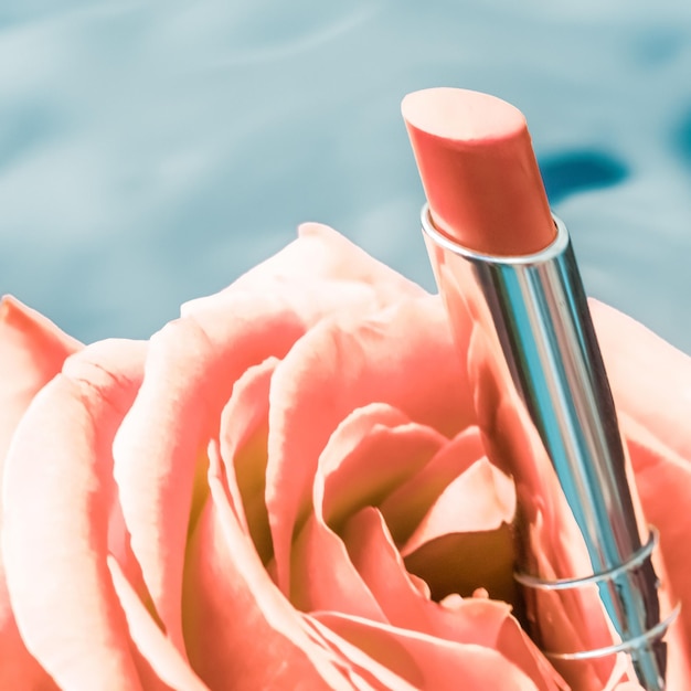 Lápiz labial amarillo y flor de rosa sobre fondo líquido maquillaje de glamour a prueba de agua y producto cosmético de brillo de labios para diseño de vacaciones de marca de belleza de lujo