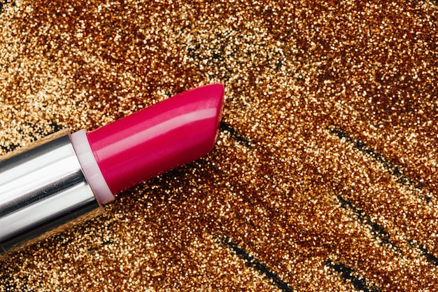 Foto lápiz labial de color rosa se encuentra en el brillo de oro