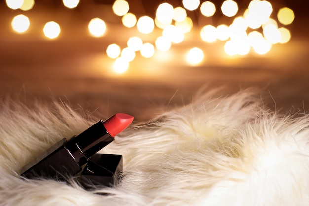 Lápiz labial de color rosa rojo en la mesa de maquillaje de belleza con luces