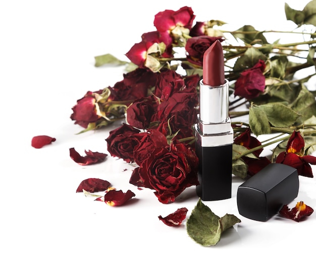 Lápiz labial y flores rosas secas