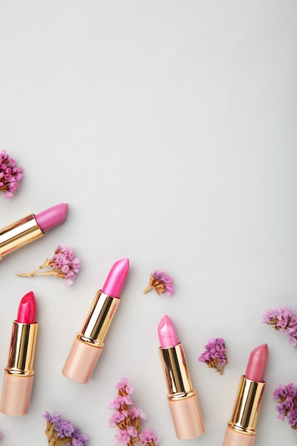 Lápiz labial con hermosas flores sobre fondo gris con espacio de copia.