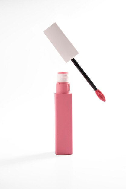 Lápiz labial líquido rosa y cepillo aplicador con tubo abierto Producto cosmético de maquillaje Fondo brillante