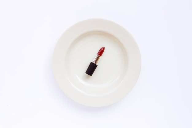 Lápiz labial en plato blanco sobre blanco.