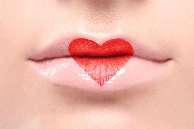 Lápiz labial rojo encantador en forma de corazón en los labios