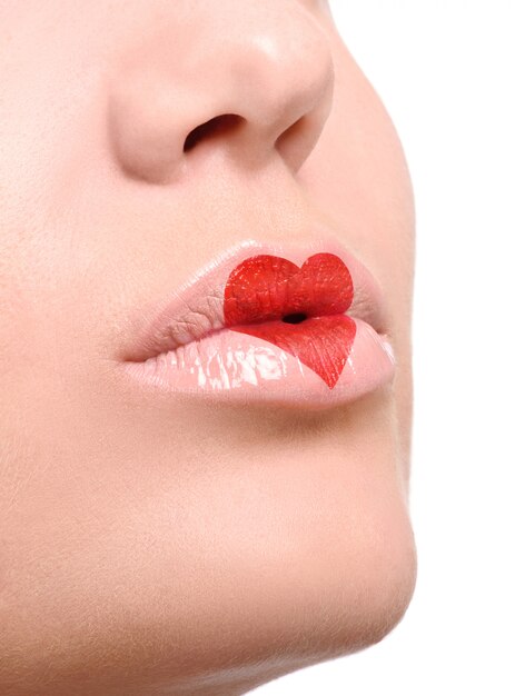 Lápiz labial rojo encantador en forma de corazón en los labios