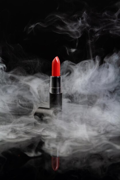 Lápiz labial rojo con vapor sobre fondo negro disparo vertical de cerca