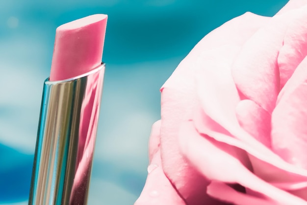 Foto lápiz labial rosa y flor de rosa sobre fondo líquido maquillaje de glamour a prueba de agua y producto cosmético de brillo de labios para diseño de vacaciones de marca de belleza de lujo