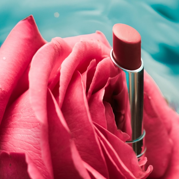 Foto lápiz labial rosa y flor de rosa sobre fondo líquido maquillaje de glamour a prueba de agua y producto cosmético de brillo de labios para diseño de vacaciones de marca de belleza de lujo