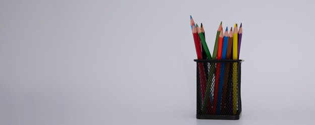 Lápiz de madera de colores en vidrio de metal negro sobre fondo blanco espacio de texto pancarta de regreso a la escuela co