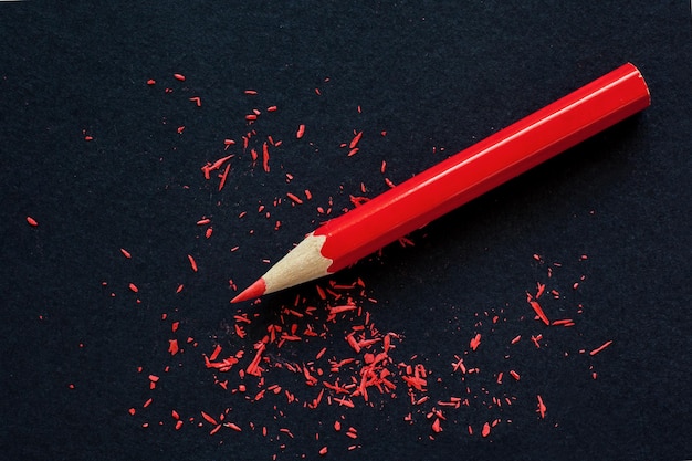 Foto lápiz de madera rojo y virutas de lápiz sobre fondo de papel negro