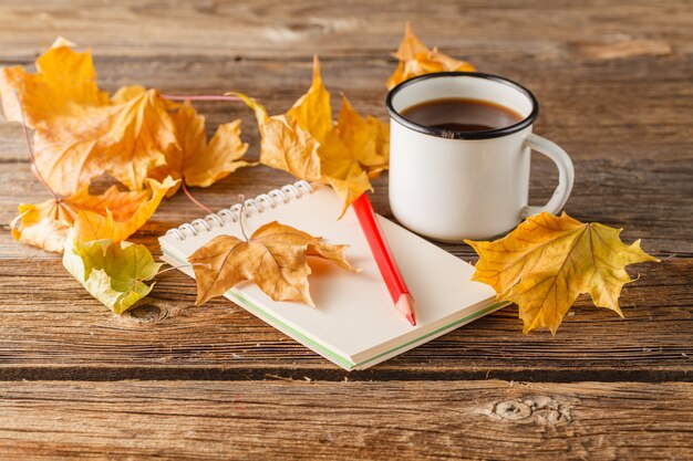 Lápiz sobre el papel vintage vacío, hojas de otoño en la mesa de madera. Concepto de regreso a la escuela: papel, lápices y hojas de colores.