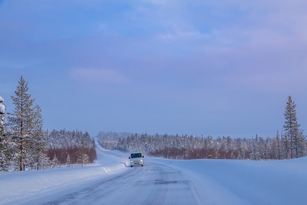 Lapônia finlandesa. estrada da floresta de inverno ao pôr do sol. ônibus solitário