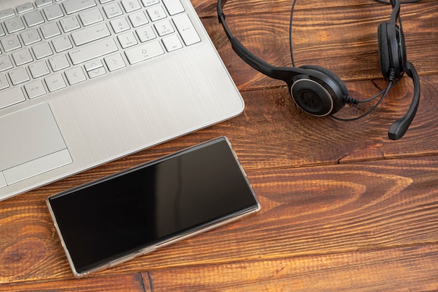 Lapto, teléfono móvil y auriculares sobre la mesa.