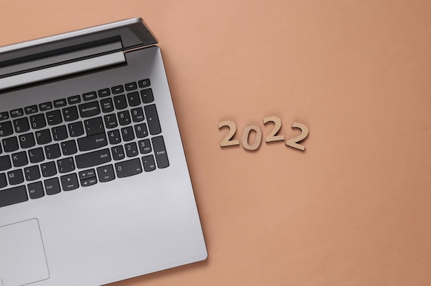 Laptop con 2022 sobre fondo marrón Composición de año nuevo