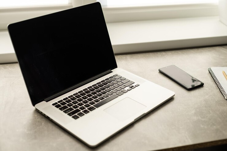 Foto laptop aberto e smartphone em cima da mesa, local de trabalho perto da janela,