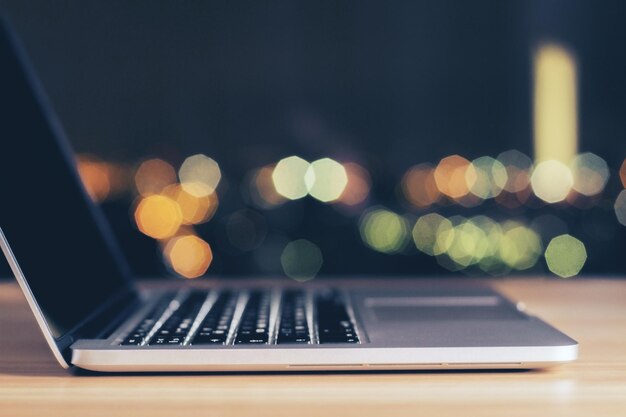 Laptop aberto na mesa de madeira à noite