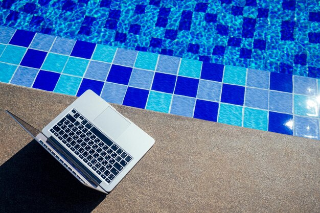 Laptop am Pool, Remote-Arbeit im Urlaub freiberuflich und Frilansing-Konzept