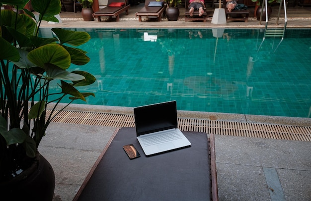 Laptop am Schwimmbad und Smartphone