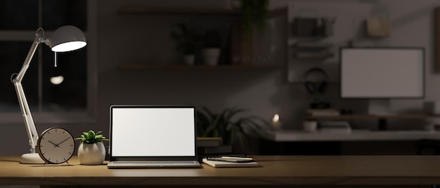 Foto laptop-attrappe wecker briefpapier dekorpflanze und tischlampe auf holztischplatte im dunklen büro