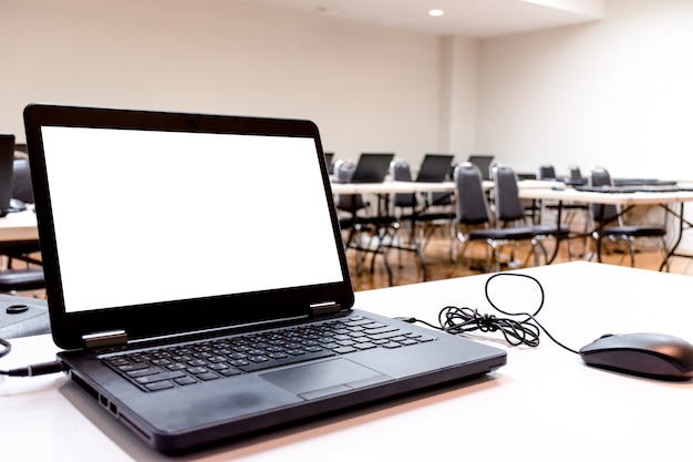 Laptop auf Tisch mit weißem Bildschirm im Schulungsraum