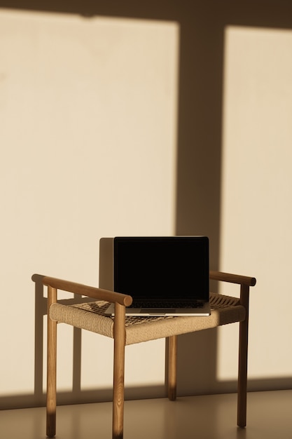 Laptop auf Weidenbank in Sonnenlichtschatten an der Wand