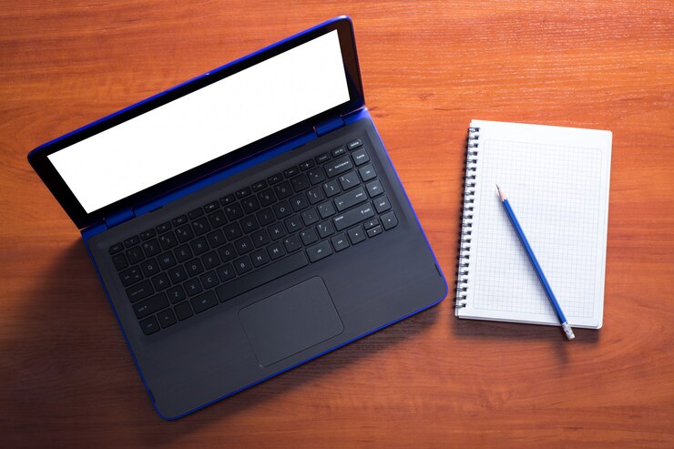 Foto laptop azul com caderno e lápis em uma mesa de madeira