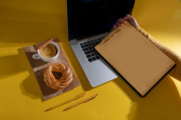 Laptop, bolo, xícara de chá e área de transferência, vista superior.