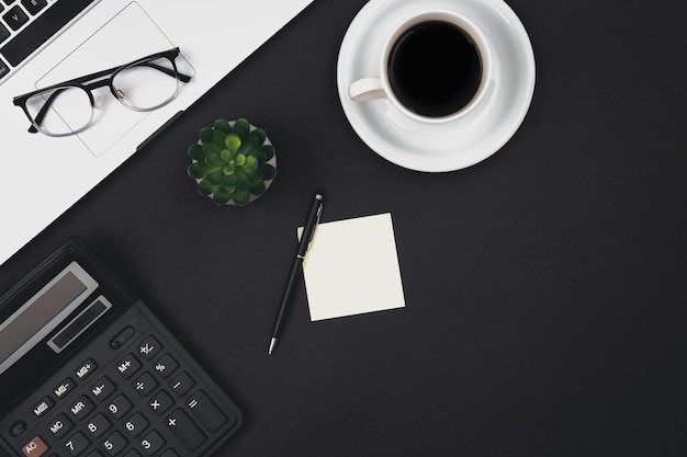 Laptop-Brille, Kaffeetasse und Taschenrechner auf schwarzem Hintergrund, Draufsicht