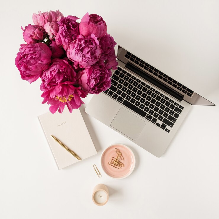 Laptop, buquê de flores de tulipa de peônia rosa linda e caderno na mesa branca. Camada plana, vista superior