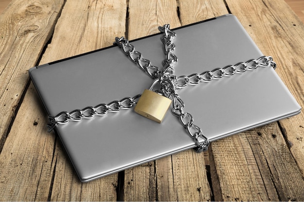 Laptop con cadenas y candado sobre fondo de madera