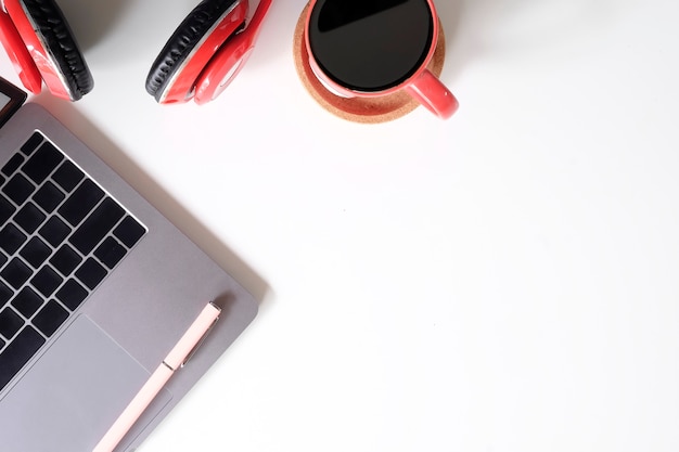 Laptop, café, pena e fones de ouvido da mesa de escritório na tabela branca.