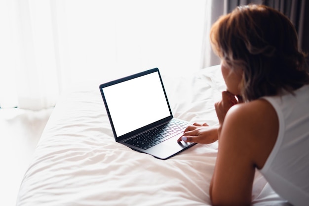 Laptop en cama vacíaMujer caucásica acostada en la cama usando una laptop