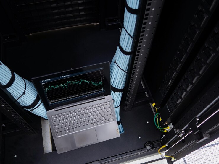 Foto laptop del centro de datos con gráfico en la pantalla por encima de los estantes