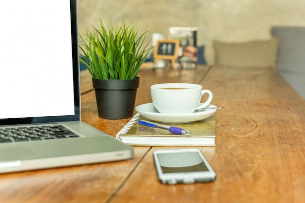 Laptop com copo de café e telefone celular na tabela de madeira no café.