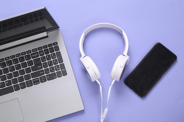 Laptop com smartphone de fones de ouvido em fundo roxo Conceito musical Vista superior