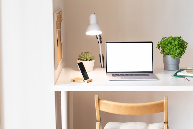 Laptop com tela branca em branco no interior da mesa de escritório. Vista de mesa de maquete de local de trabalho de ouro rosa elegante.