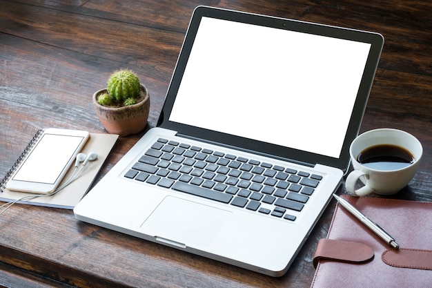 Laptop com tela branca em branco sobre a mesa de escritório de madeira.