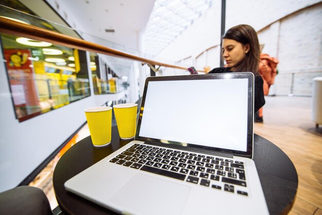 Laptop com tela branca no café mulher com telefone no conceito de estilo de vida de fundo