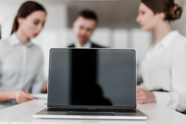 Laptop com tela em branco na frente do grupo de colegas de trabalho