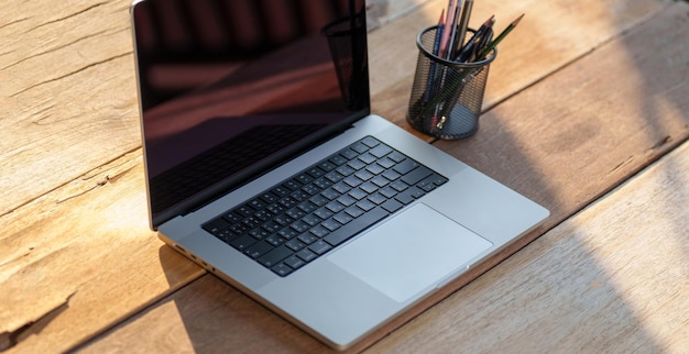 Laptop com tela preta em branco em uma mesa de madeira