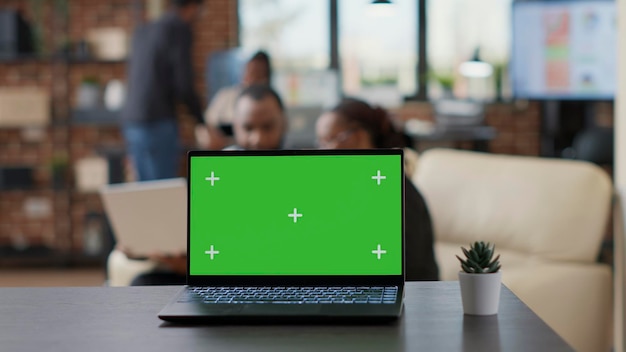 Laptop com tela verde na mesa no escritório de negócios, equipe de pessoas com espaço de cópia em branco isolado com croma backgorund e modelo de maquete. tecnologia moderna. fechar-se.