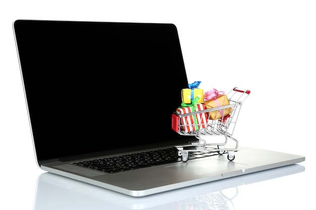 Laptop com um pequeno carrinho de compras cheio de presentes isolados no fundo branco