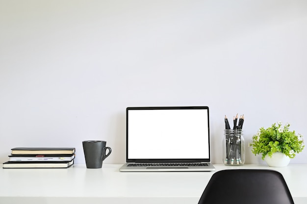 Laptop-Computer am Arbeitsplatz mit Stuhl, Kaffee, Notebook-Papier und Bleistift.