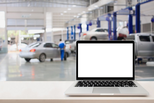 Laptop-Computer auf Holztisch mit unscharfem Auto-Service-Center-Hintergrund