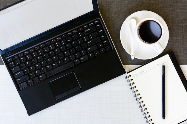 Laptop-Computer, Kaffeetasse und Notizbuch auf dem Tisch