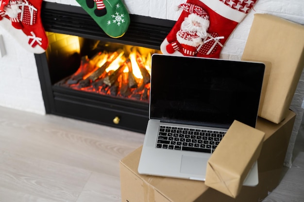 Laptop-Computer mit weißem leerem leerem Bildschirm an frohen Weihnachten mit Geschenken. E-Commerce-Website Online-Shopping-Lieferanzeigen.