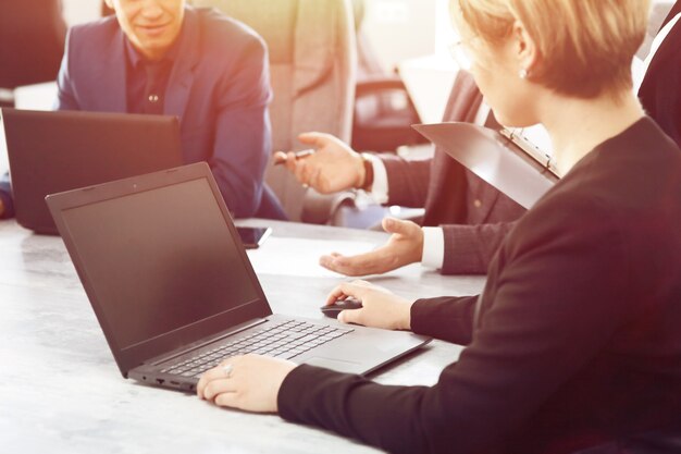 Laptop contra un grupo de jóvenes empresarios en la oficina discutiendo una idea de trabajo juntos