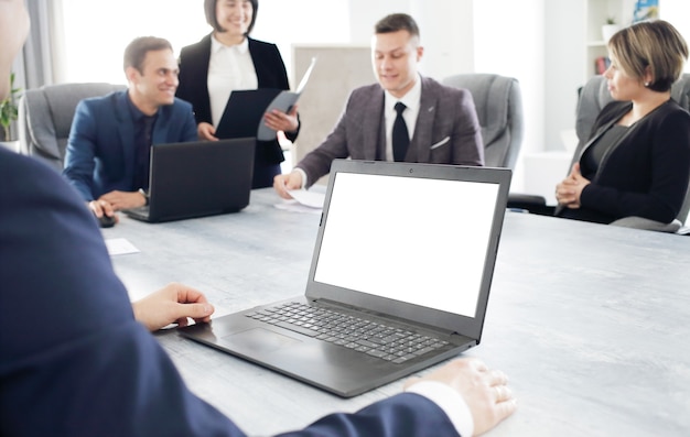 Laptop contra um grupo de jovens empresários no escritório discutindo uma ideia de trabalho juntos