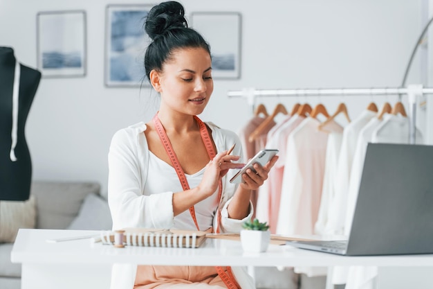 Con laptop La costurera está en su oficina con ropa diferente