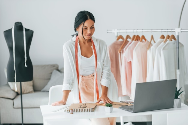 Con laptop La costurera está en su oficina con ropa diferente